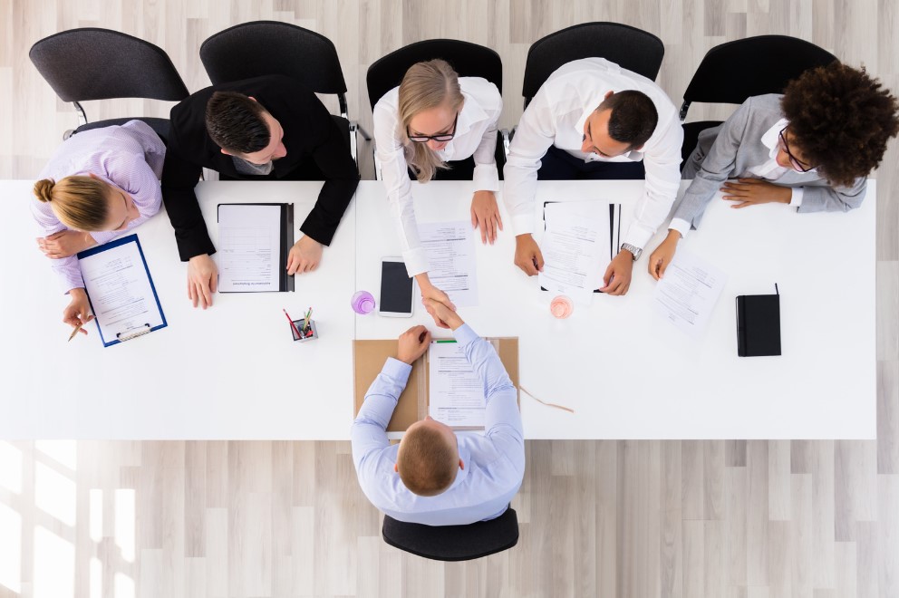 Top-down view of a job interview panel meeting a candidate, highlighting mission-driven hiring strategies focused on values and organizational impact.