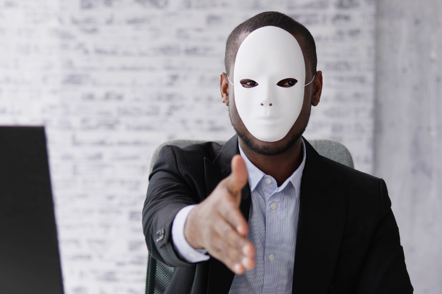 Masked individual extending a handshake, highlighting the importance of steps to avoid LinkedIn hiring scams.